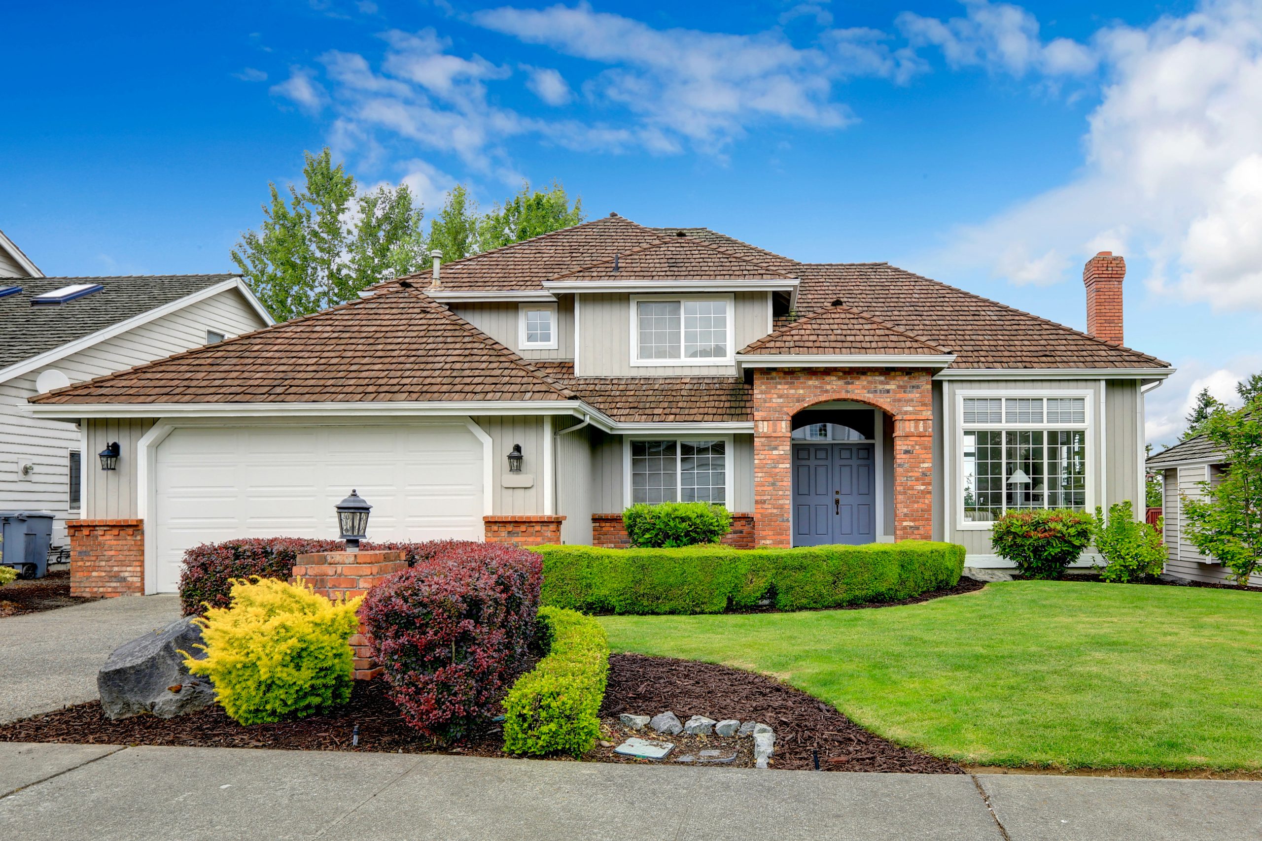 Red brick house with aa brown roof and a green front yard