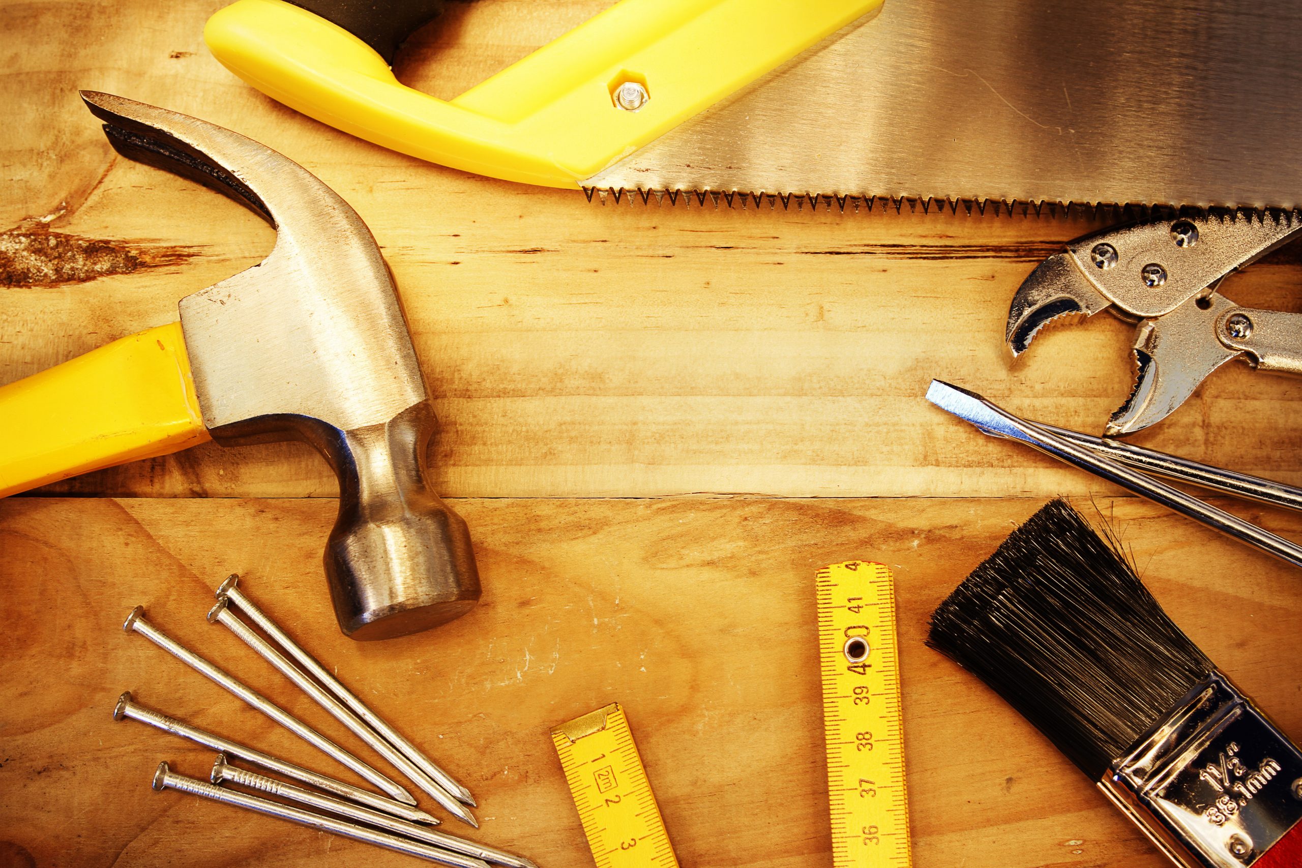 Variety of tools with yellow handles on a wood table